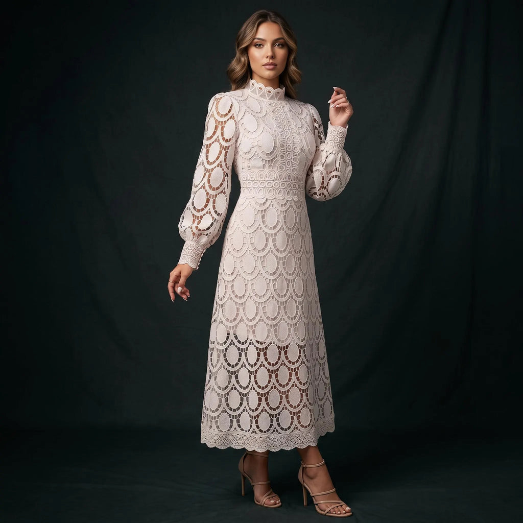 A woman modeling a high-neck, long-sleeve lace midi dress in cream or off-white, standing against a dark studio backdrop. The dress features an intricate floral lace pattern with scalloped edges and sheer sections.